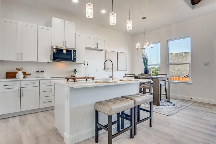 Kitchen with decorative backsplash, decorative light fixtures, white cabinetry, light wood-style floors, and recessed lighting Kitchen with decorative backsplash, decorative light fixtures, white cabinetry, light wood-style floors, and recessed lighting