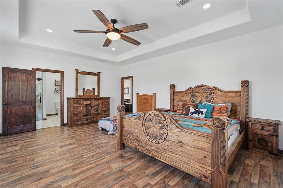 Bedroom with a raised ceiling, wood finished floors, a ceiling fan, and recessed lighting Bedroom with a raised ceiling, wood finished floors, a ceiling fan, and recessed lighting