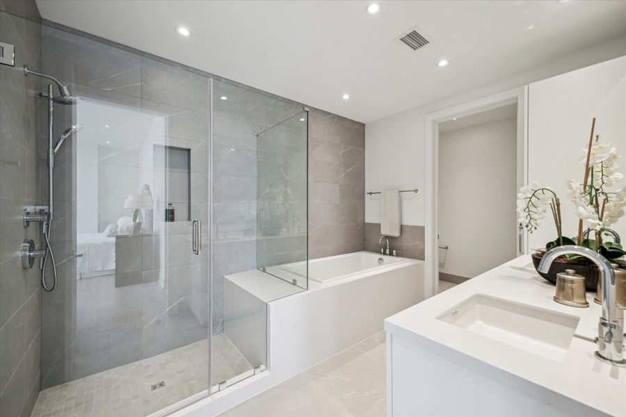 Separate step-in shower with hand held sprayer, bench seat and niche.