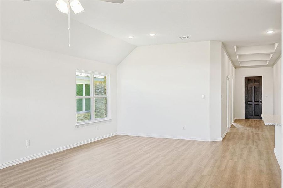 Unfurnished room with ceiling fan, vaulted ceiling, and light wood-type flooring