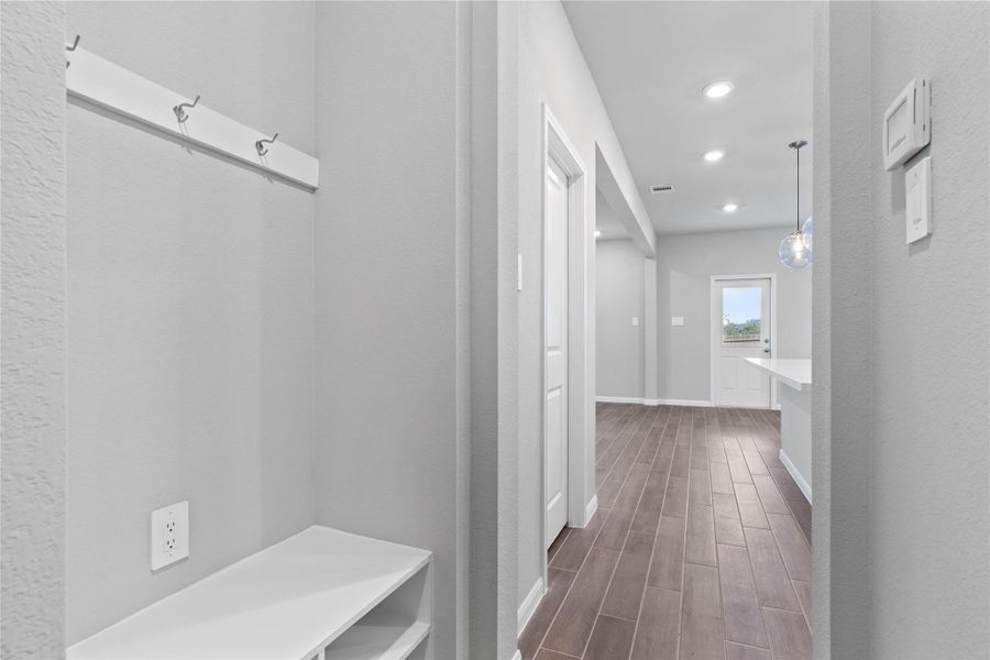 This dedicated area features a custom built-in bench with hooks, perfect for organizing coats, bags, and shoes right off the main hallway, keeping the rest of the home tidy.