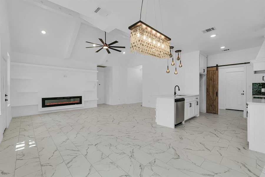 Unfurnished living room with ceiling fan, a barn door, light tile patterned flooring, and beamed ceiling