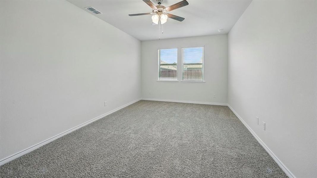 Spacious interior room featuring light gray carpet flooring, white painted walls, white baseboards, and a ceiling fan with integrated lighting