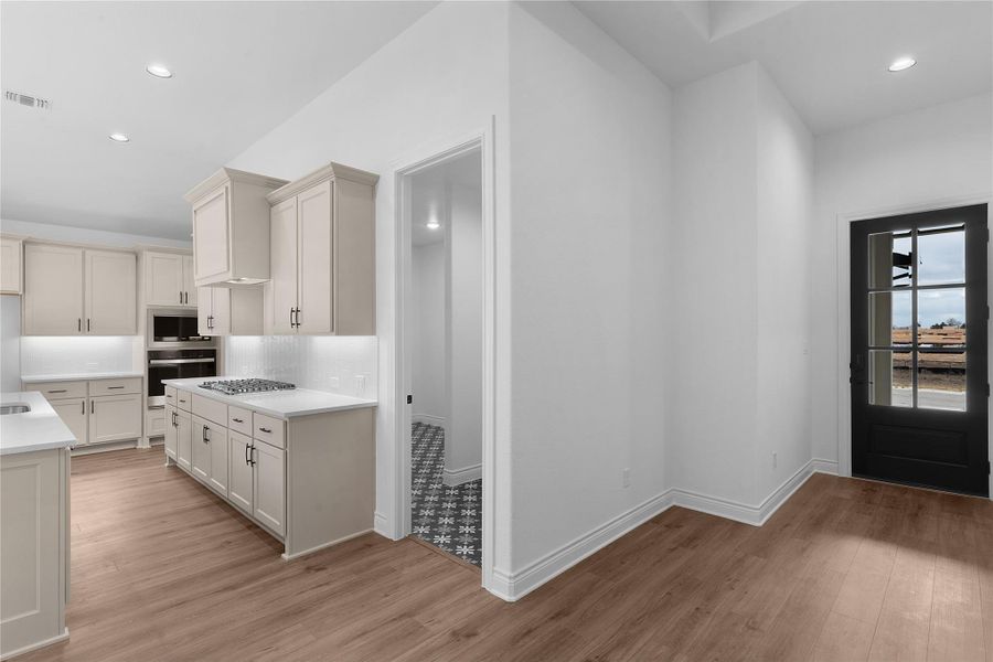 Kitchen with recessed lighting, light wood-style flooring, stainless steel appliances, decorative backsplash, and light stone countertops