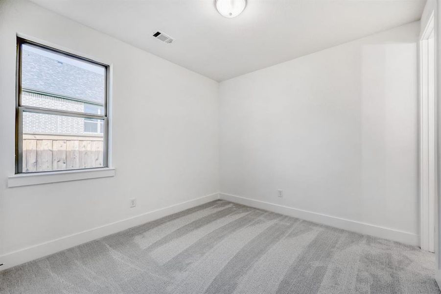 Empty room with light colored carpet and baseboards