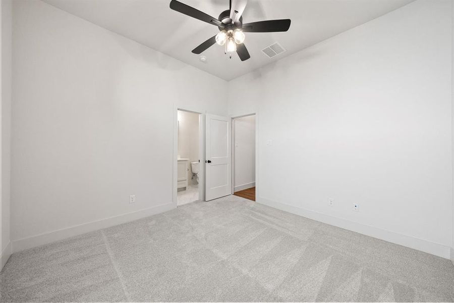 Unfurnished bedroom with light carpet, a ceiling fan, and connected bathroom