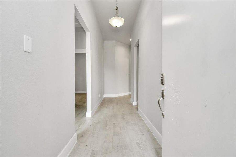 The majestic entryway allures with its high ceilings, embellished with sophisticated wood-look tile flooring and sleek oversized baseboards.