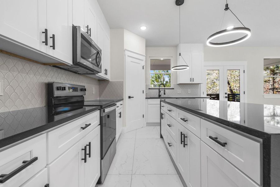 Stainless steel Stove, dishwasher, decorative light fixtures, white cabinetry & backsplash