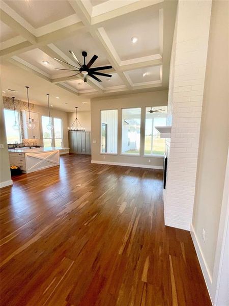 Unfurnished living room with ceiling fan, coffered ceiling, a fireplace, dark wood-type flooring, and recessed lighting