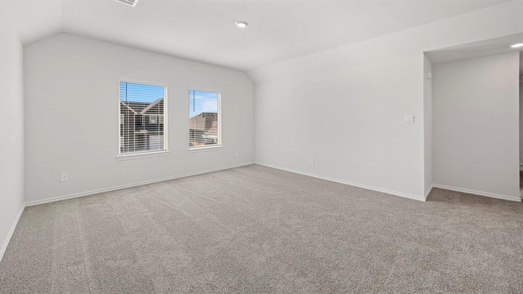 Additional living space featuring light colored carpet and vaulted ceiling