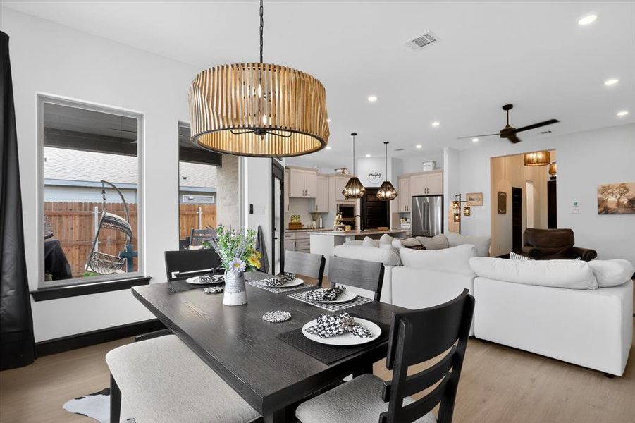Dining area with a striking drum chandelier and wood-finish flooring