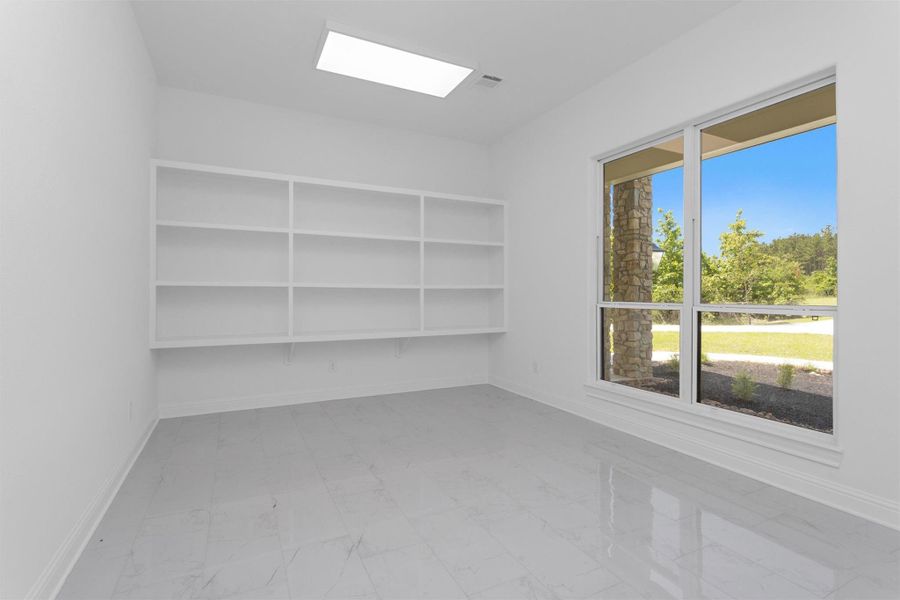 This versatile bonus room features built-in shelving, abundant natural light, and sleek tile flooring—ideal for a craft room, extra pantry or tech hub.