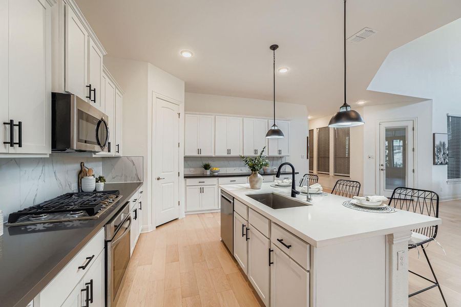 Kitchen with a breakfast bar area, white cabinetry, pendant lighting, a center island with sink, and recessed lighting Kitchen with a breakfast bar area, white cabinetry, pendant lighting, a center island with sink, and recessed lighting