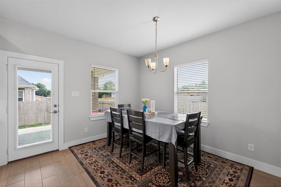 Dining area with light gray walls, a modern chandelier, and two windows providing natural light