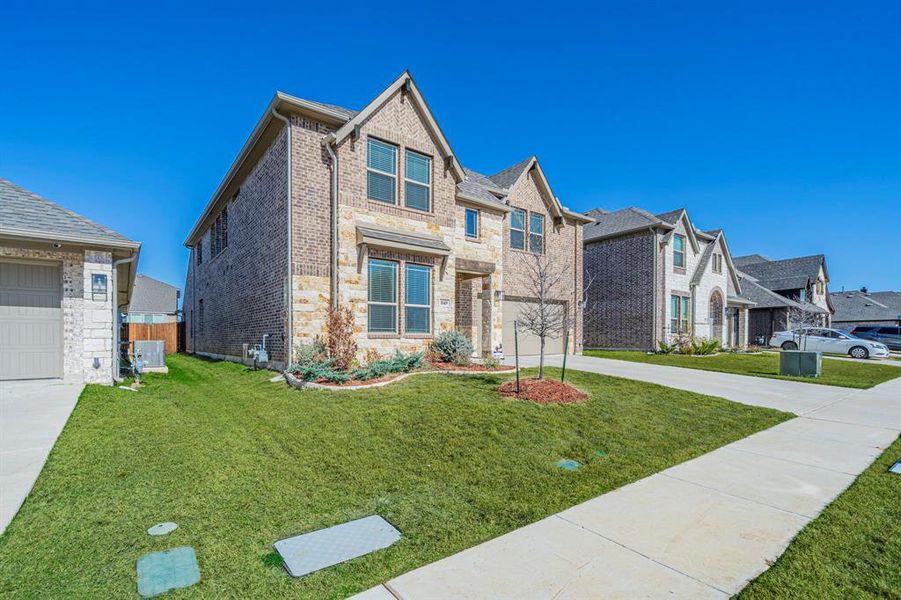 Two-story residence featuring a brick and stone facade, gabled rooflines, and a well-maintained lawn