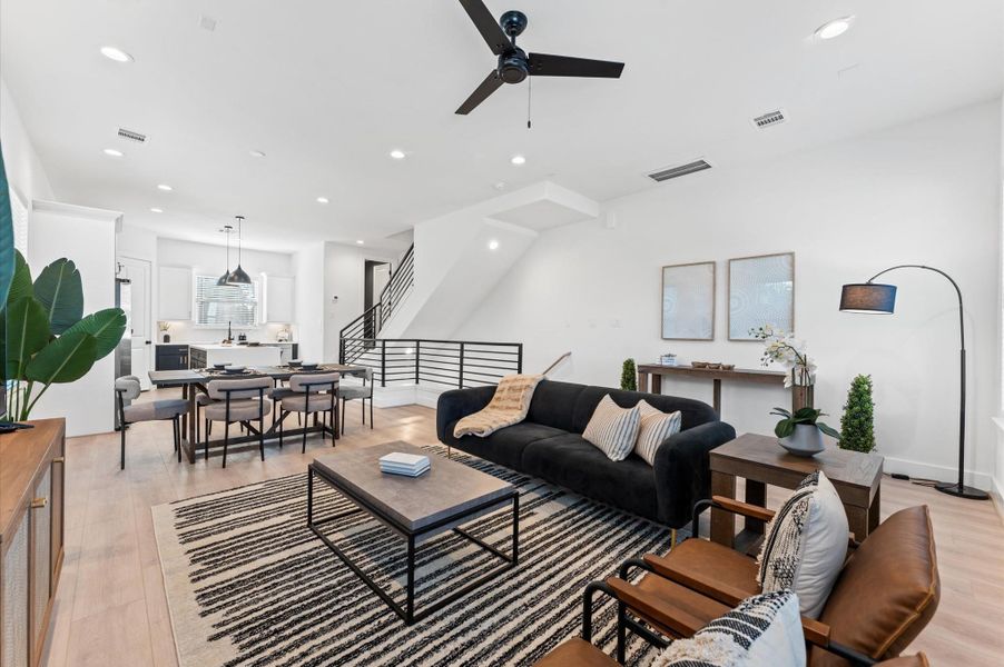 Open-concept living space with sleek hardwood floors, modern fixtures, and abundant natural light, seamlessly connecting the living area, dining space, and contemporary kitchen.
