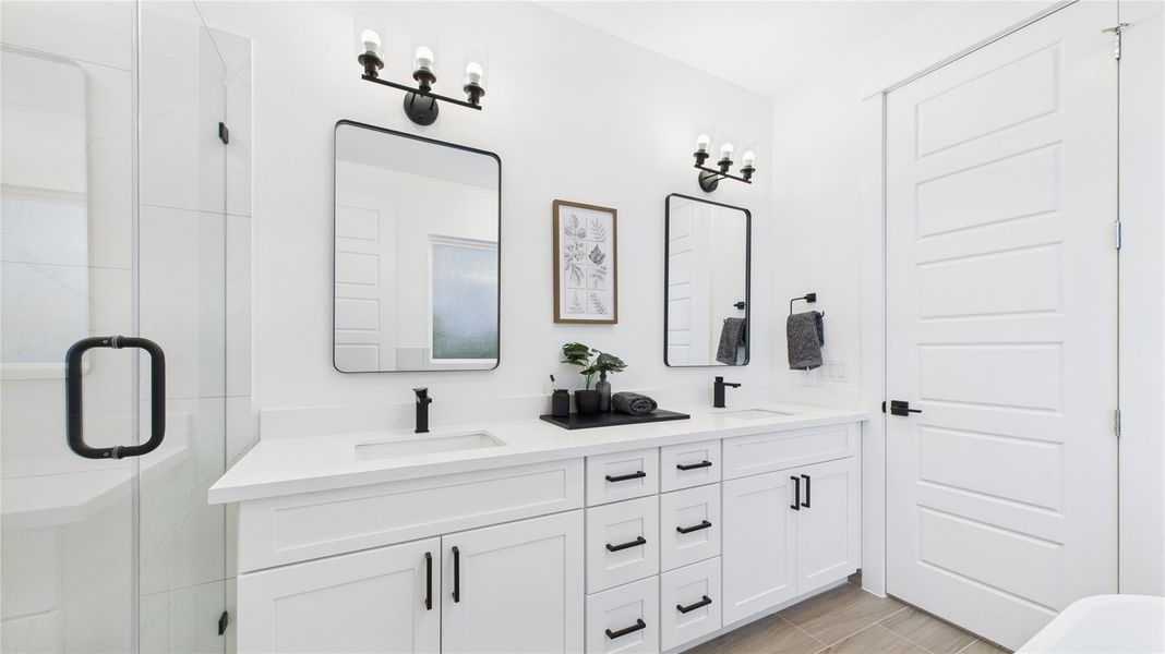 This stylish primary bathroom showcases a spacious walk-in shower framed with sleek glass panels and modern tilework that adds texture and sophistication. A double sink vanity anchors the space with clean lines and ample countertop room, complemented by an abundance of cabinetry that offers both function and flair. Contemporary finishes tie the room together, creating a polished retreat that balances luxury with everyday practicality.