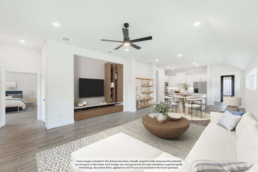 Open-concept living room with ceiling fan, built-in wood shelving, and view into kitchen and dining area
