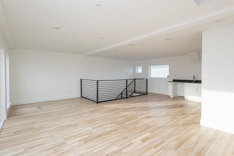 Unfurnished room with a sink, light wood-style flooring, and baseboards