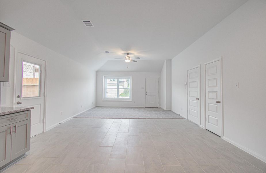 Spacious open-concept living area with high ceilings, abundant natural light from a large window, and modern tile flooring, perfect for comfortable living and entertaining.