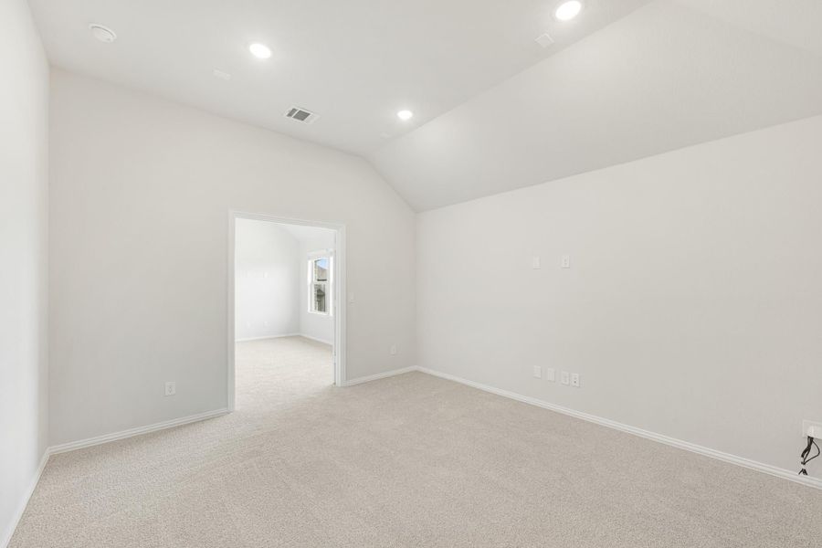 Empty bedroom with vaulted ceiling, recessed lighting, and neutral carpet flooring