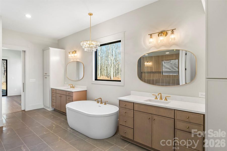 This spa-inspired primary bath feels like a five star resort with a soaking tub beneath a beautiful chandelier, an expansive zero entry shower and tons of storage.