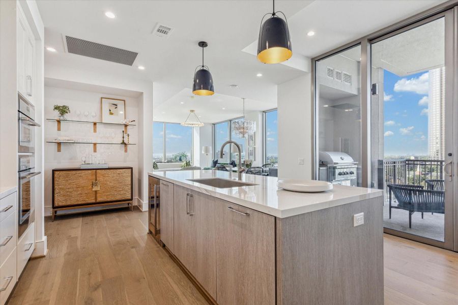 Another kitchen perspective with center island and sliding door leading to the outdoor terrace. Photos are of a similar unit with the same floor plan.