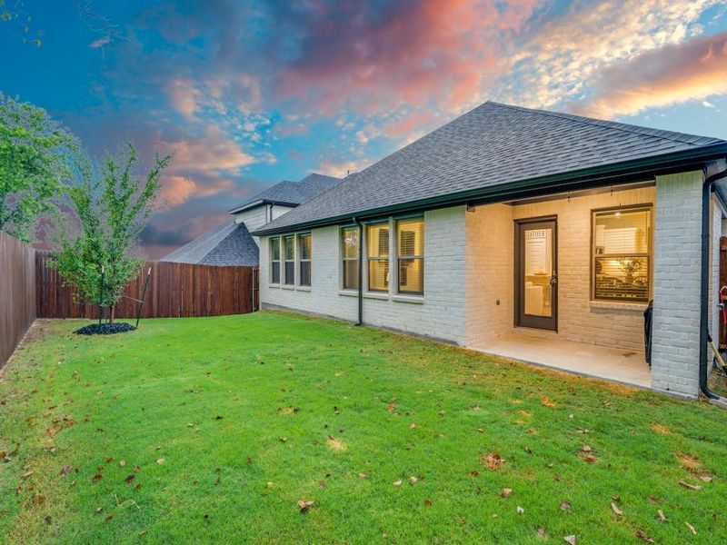 Back house at dusk with a yard and a patio area