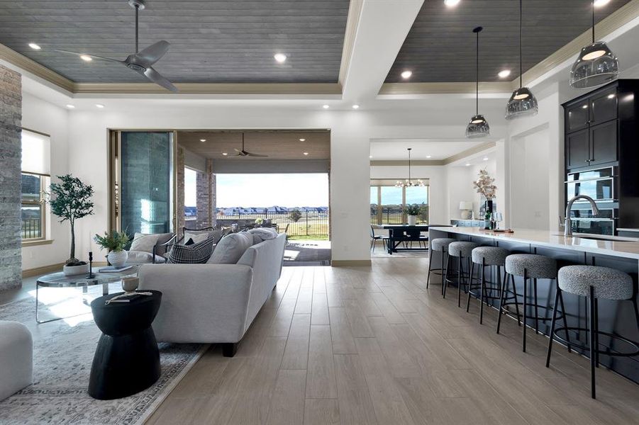 Living room with a ceiling fan, a raised ceiling, light wood finished floors, wood ceiling, and ornamental molding