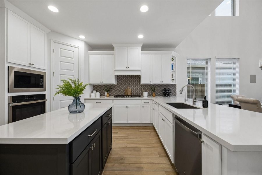 This stylish kitchen is ready for everything from quick weekday meals to weekend entertaining with quartz countertops, designer tile backsplash, sleek stainless-steel appliances, and a walk-in pantry. The contrasting island adds extra prep and storage space, while bar seating at the dining area keeps everyone connected.