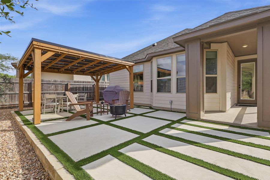 An inviting backyard patio features concrete pavers, a sturdy wooden pergola, and a covered porch area.