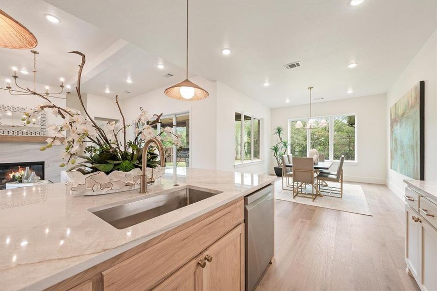 Kitchen featuring a notable chandelier, stainless steel dishwasher, light hardwood / wood-style floors, light brown cabinetry, and sink