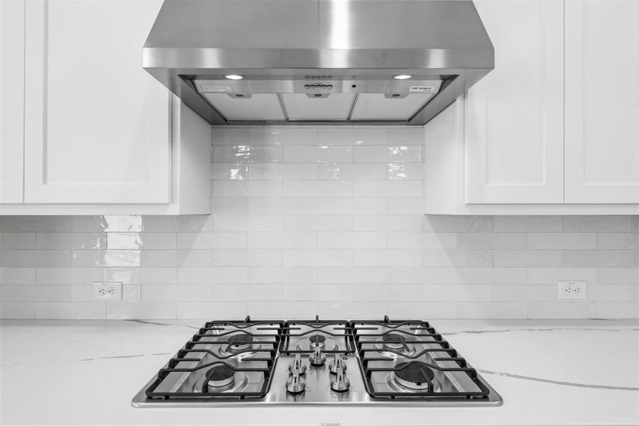 Culinary delights await with this sleek gas cooktop, complete with a stainless steel range hood.