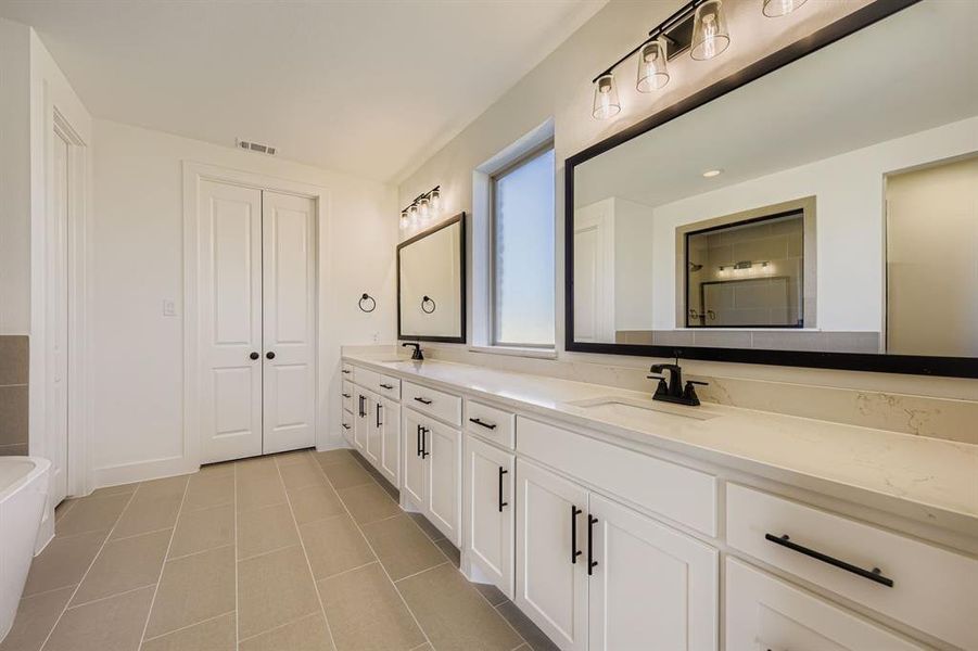 Bathroom with double vanity, light tile patterned floors, and a soaking tub