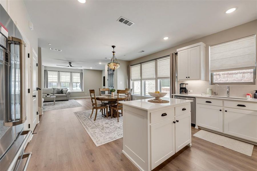Kitchen featuring white cabinetry, stainless steel appliances, a center island, and upgraded Pergo water tight laminate wood look flooring Kitchen featuring white cabinetry, stainless steel appliances, a center island, and upgraded Pergo water tight laminate wood look flooring