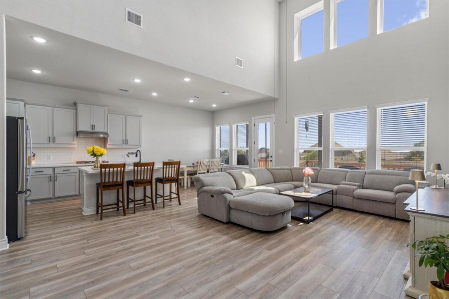 Double-height walls and large windows illuminate the open-concept living area and adjacent kitchen.