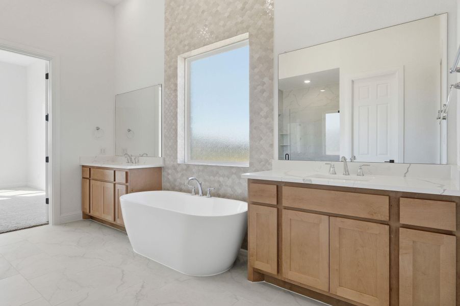 Bathroom featuring a shower stall, two vanities, a soaking tub, and light marble finish flooring