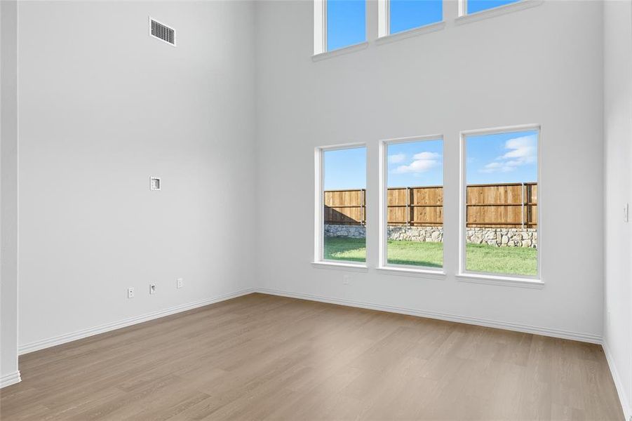 Empty room with light wood finished floors and a high ceiling Empty room with light wood finished floors and a high ceiling