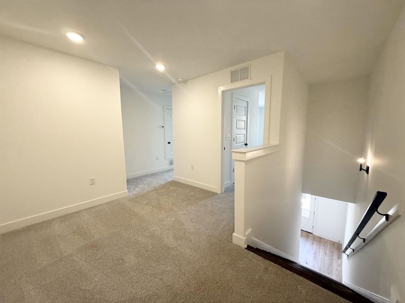 Hallway featuring an upstairs landing, dark colored carpet, and recessed lighting