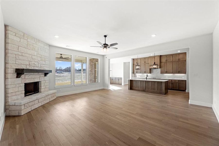 Unfurnished living room featuring ceiling fan, a fireplace, sink, and light hardwood / wood-style flooring