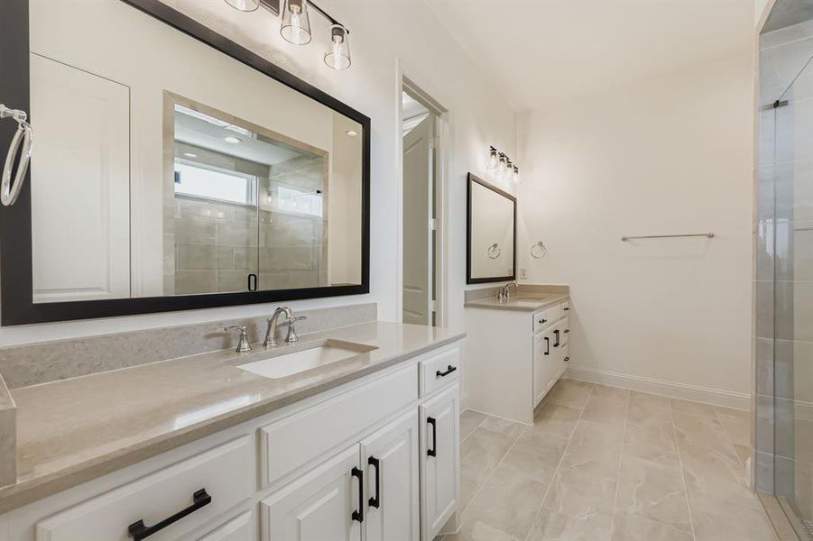 Bathroom with a stall shower, two vanities, and light tile patterned flooring