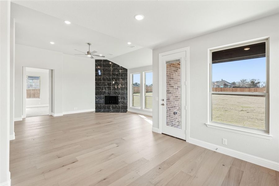 Open living room with light hardwood floors, black marble fireplace, and ceiling fan Open living room with light hardwood floors, black marble fireplace, and ceiling fan