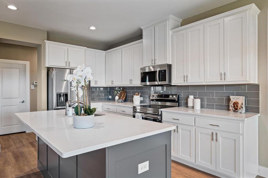 Kitchen with a kitchen island with sink, white cabinets, and stainless steel appliances