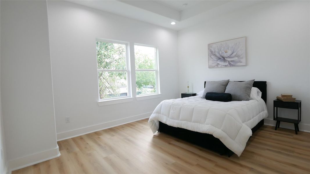 This bedroom is bright and airy, featuring light wood flooring, a large window allowing natural light, and a cozy bed with modern decor. This bedroom is bright and airy, featuring light wood flooring, a large window allowing natural light, and a cozy bed with modern decor.