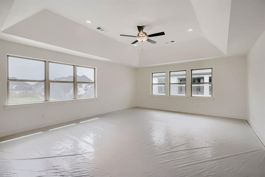 Spacious room featuring multiple large windows, a tray ceiling, recessed lighting, and a ceiling fan Spacious room featuring multiple large windows, a tray ceiling, recessed lighting, and a ceiling fan