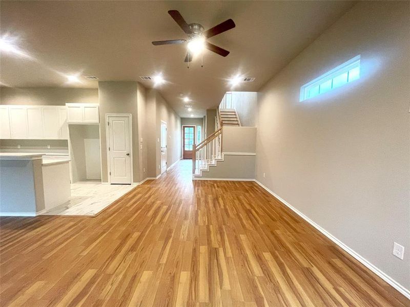 Unfurnished living room with a ceiling fan, light wood-type flooring, stairway, and baseboards