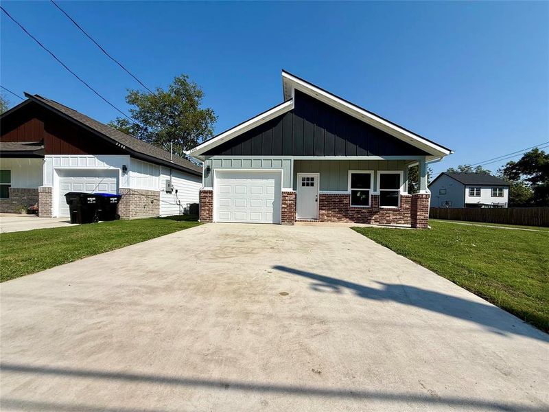 View of front of home featuring board and batten siding, a front lawn, an attached garage, and driveway