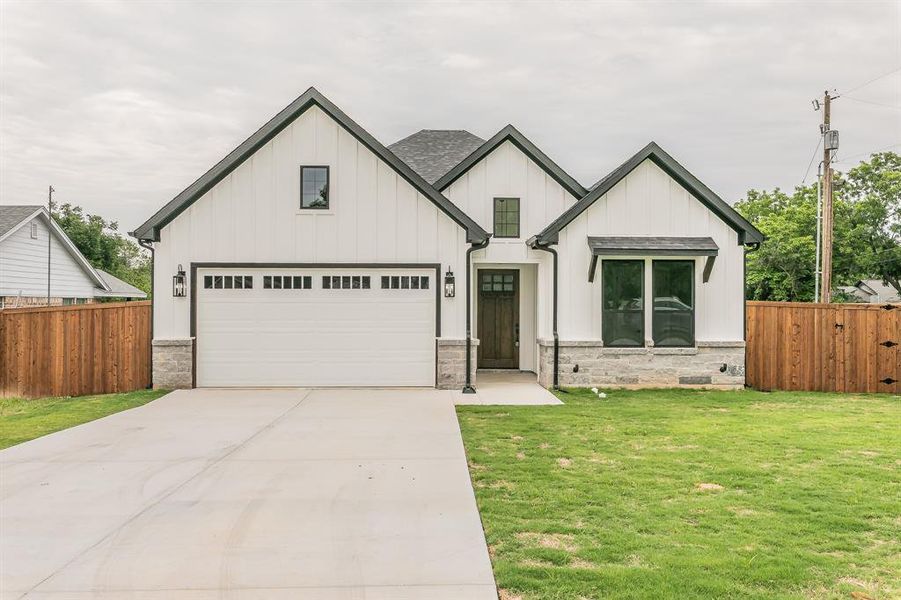 Modern inspired farmhouse featuring board and batten siding, driveway, roof with shingles, and stone siding Modern inspired farmhouse featuring board and batten siding, driveway, roof with shingles, and stone siding