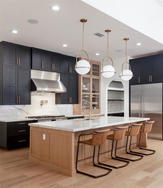 Example of Builders previously built home with similar finishes. Example of a kitchen featuring custom two-toned cabinets, a built-in hutch, and an open pantry with built-in cabinetry and floating shelves. Anchored by a 10-foot island with seating, the space balances casual comfort with refined style. Example of Builders previously built home with similar finishes. Example of a kitchen featuring custom two-toned cabinets, a built-in hutch, and an open pantry with built-in cabinetry and floating shelves. Anchored by a 10-foot island with seating, the space balances casual comfort with refined style.