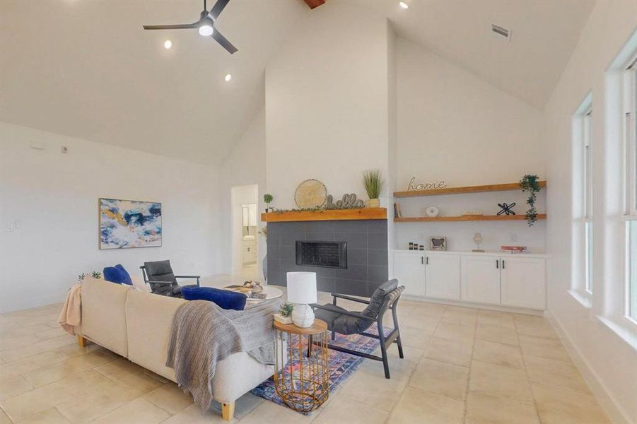 Living room with high vaulted ceiling, a tiled fireplace, recessed lighting, a ceiling fan, and light tile patterned floors Living room with high vaulted ceiling, a tiled fireplace, recessed lighting, a ceiling fan, and light tile patterned floors